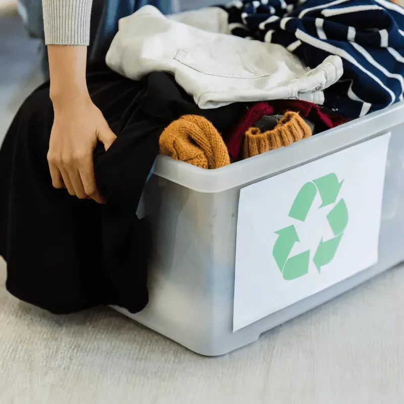 Kiste mit Kleidung und Recycling-Symbol – Wiederverwertung statt Müll